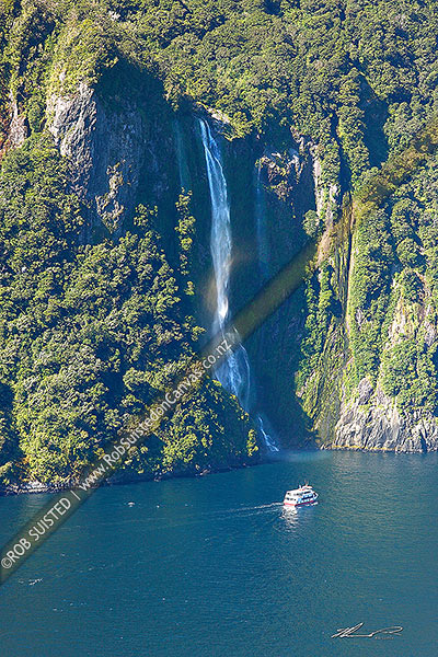 Photo of Stirling Falls (146m) spilling from a glaciated hanging valley into Milford Sound. With tour boat below, Milford Sound, Fiordland National Park, Southland, Southland Region, New Zealand (NZ)