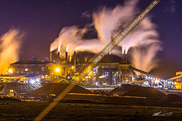 Photo of Glenbrook Steel Mill seen at night, producing steel from coastal ironsands ore, a unique utilisation. Steam billowing from stacks, Waiuku, Papakura, Auckland Region, New Zealand (NZ)