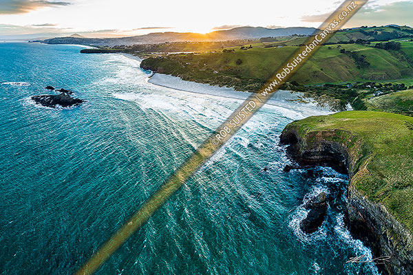 Photo of Dunedin South Coast, looking along Smaills Beach to Tomahawk Beach, Lawyers Head and St Kilda behind. Bird Island at left. Aerial view at sunset, from near Maori Head, Otago Peninsula, Dunedin City, Otago Region, New Zealand (NZ)