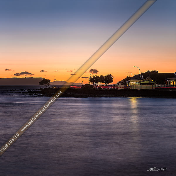 Photo of Plimmerton Beach sunset with traffic and vehicle lights passing on Sunset Parade road. Mana Island left and South Island in distance. Square format, Plimmerton, Porirua City, Wellington Region, New Zealand (NZ)